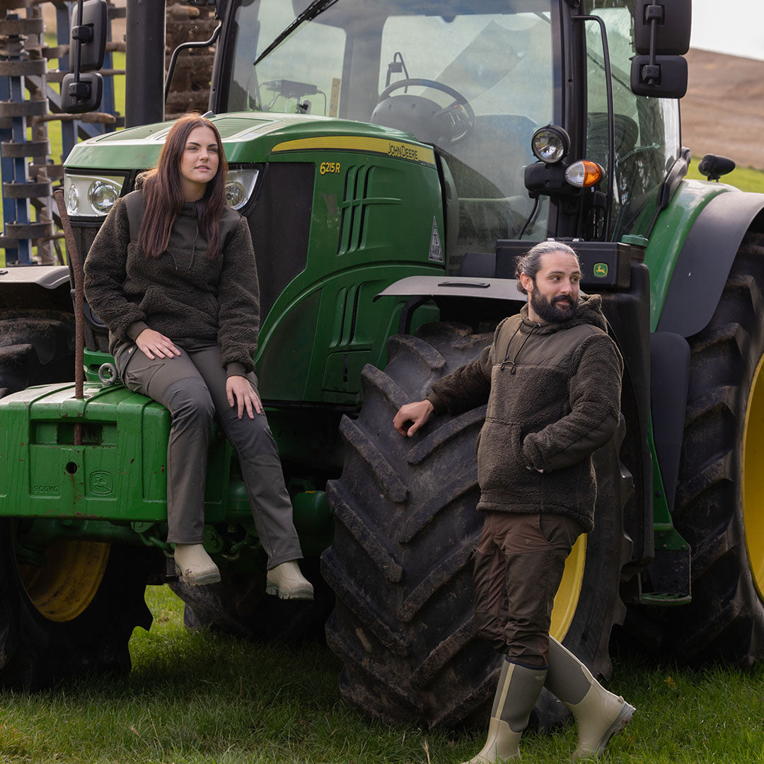 Green John Deere tractor next to Jack Pyke Sherpa Fleece Hoodie Gen 2 for a cozy style