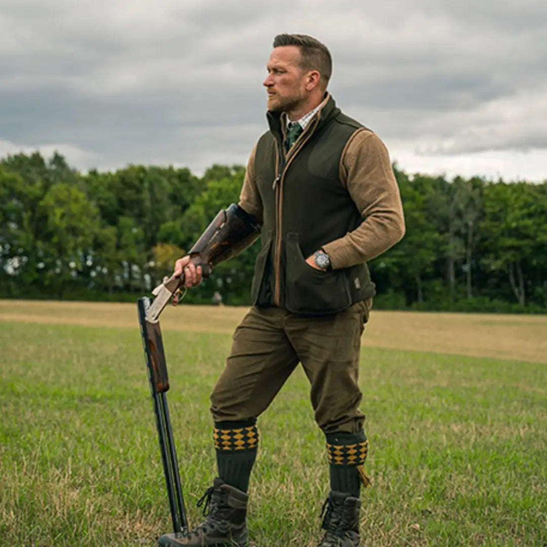 Man in hunting gear with a shotgun wearing Jack Pyke’s Shooters Gilet in a field