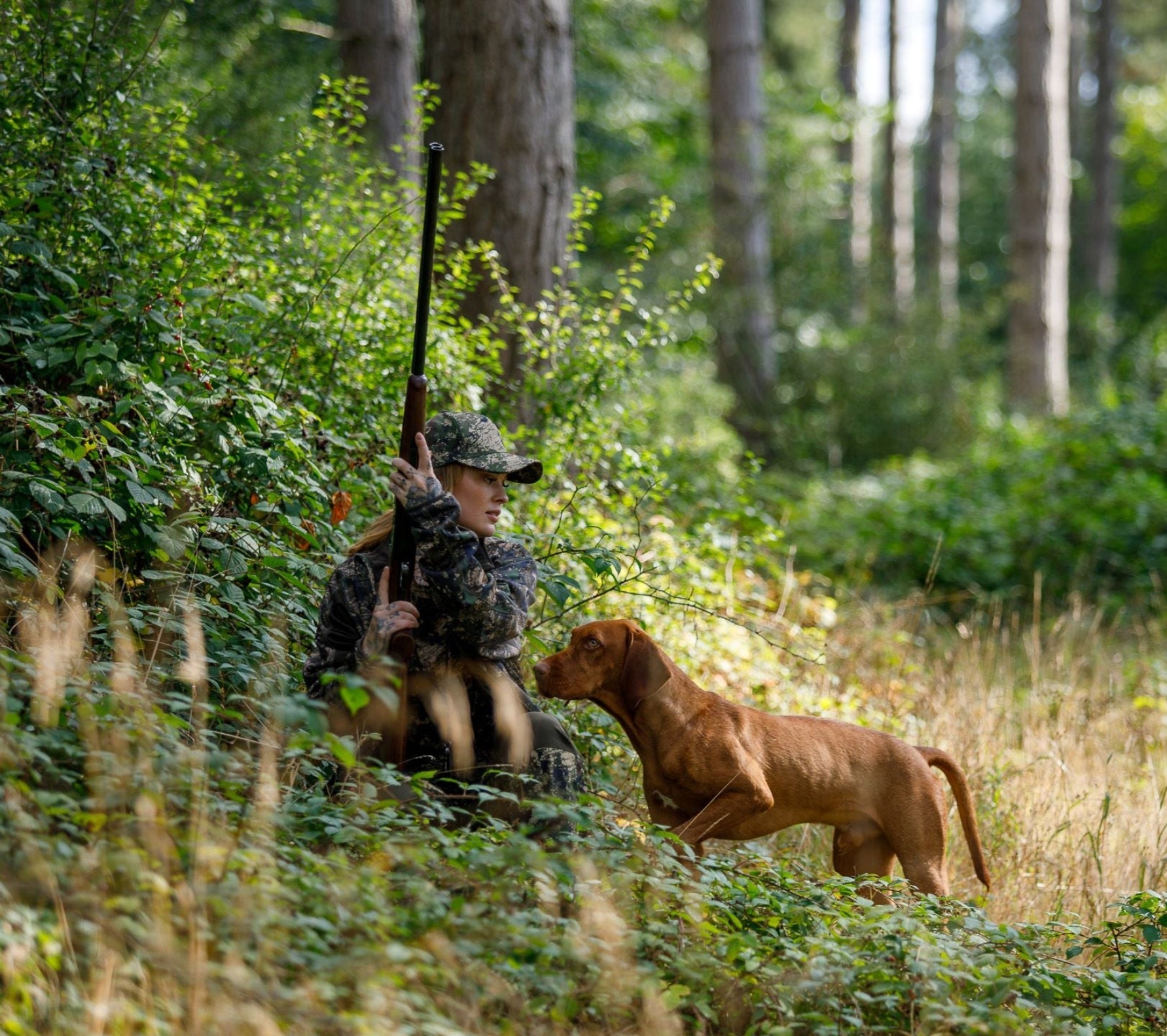 Hunter with dog and rifle wearing a Jack Pyke Softshell Baseball Cap outdoors