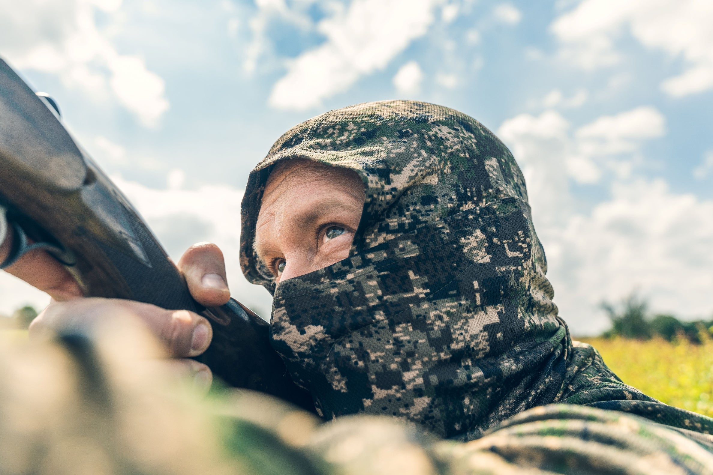 Camouflaged hunter aiming with a rifle wearing Jack Pyke Stealth Balaclava