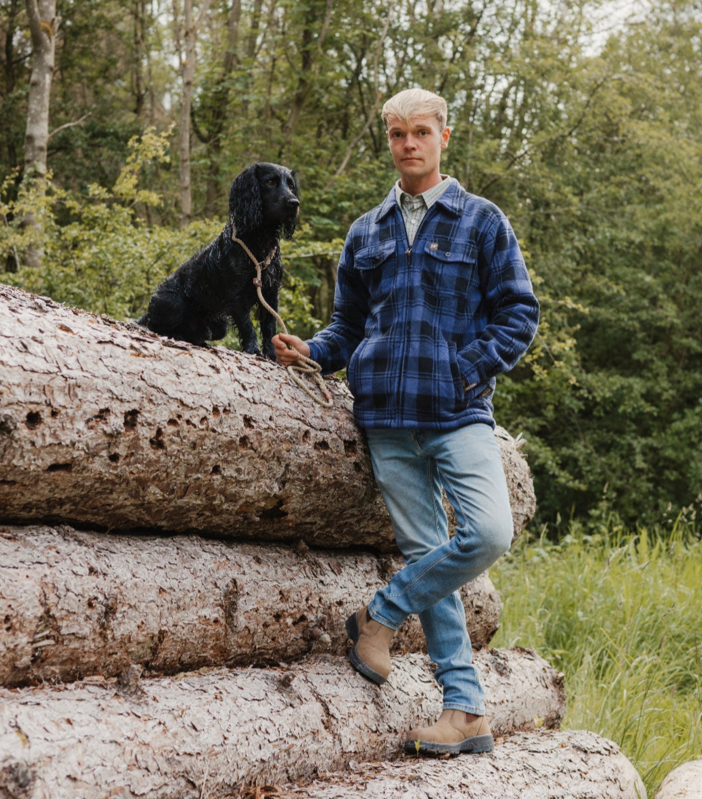 Man and dog on logs wearing Jack Pyke Tundra Shirt, perfect for outdoor adventures