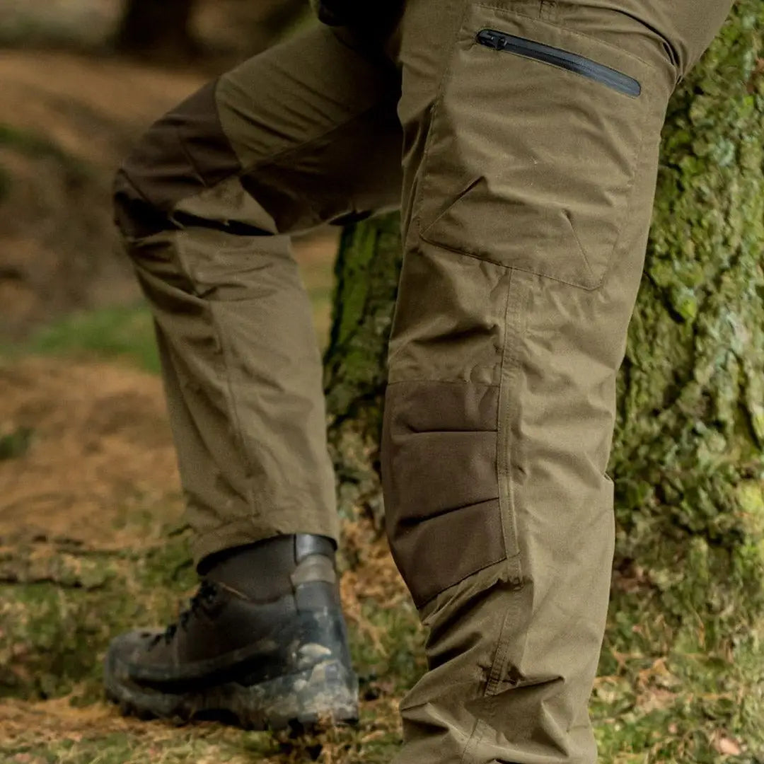 Pair of Jack Pyke Weardale Hunting Trousers with pockets by a mossy surface