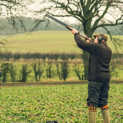 Hunter in Jack Pyke Weardale Knitted Jacket aiming shotgun in a field