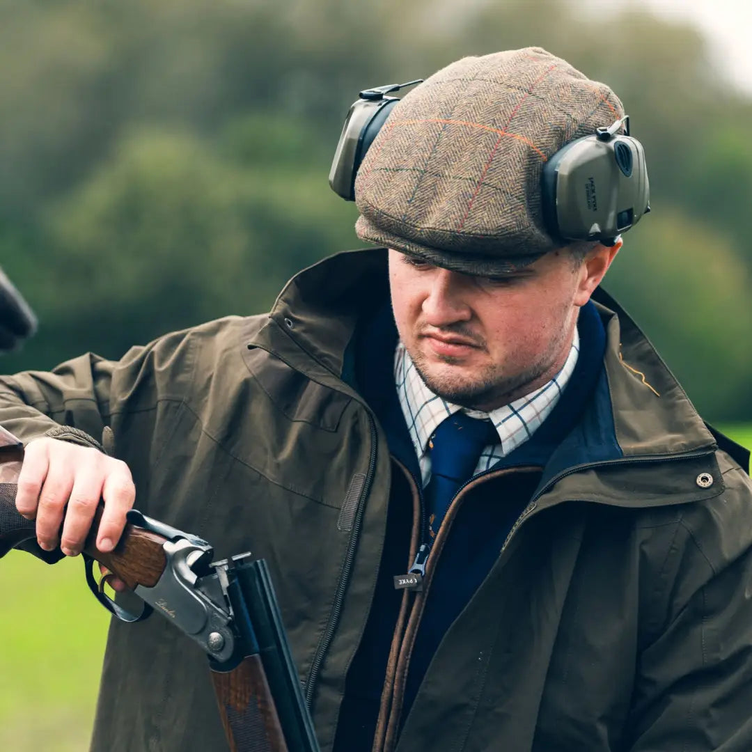 Man in Jack Pyke Wool Blend Flat Cap and ear protectors, holding a shotgun