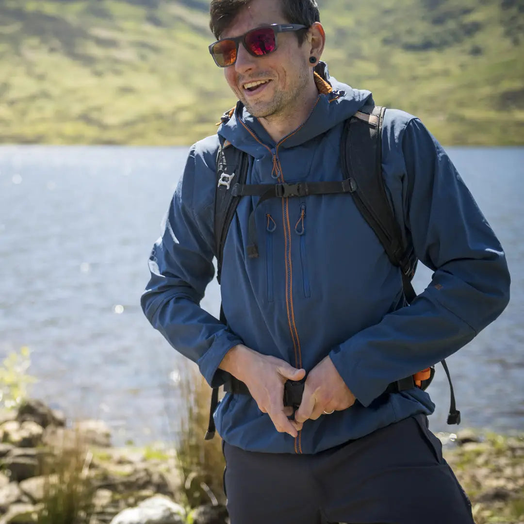 Smiling hiker in a blue Keela Hydron Softshell jacket and backpack with sunglasses