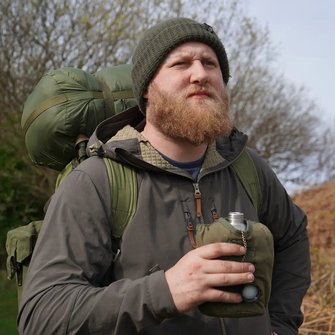 Bearded guy in outdoor gear with a drink, showing off his Keela Hydron Softshell Jacket