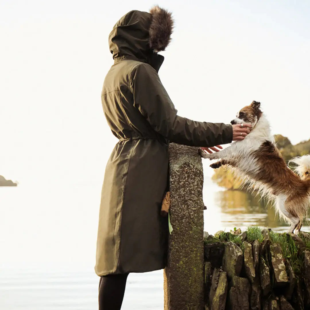 Person in a long coat petting a dog while wearing a stylish Crofter Parka