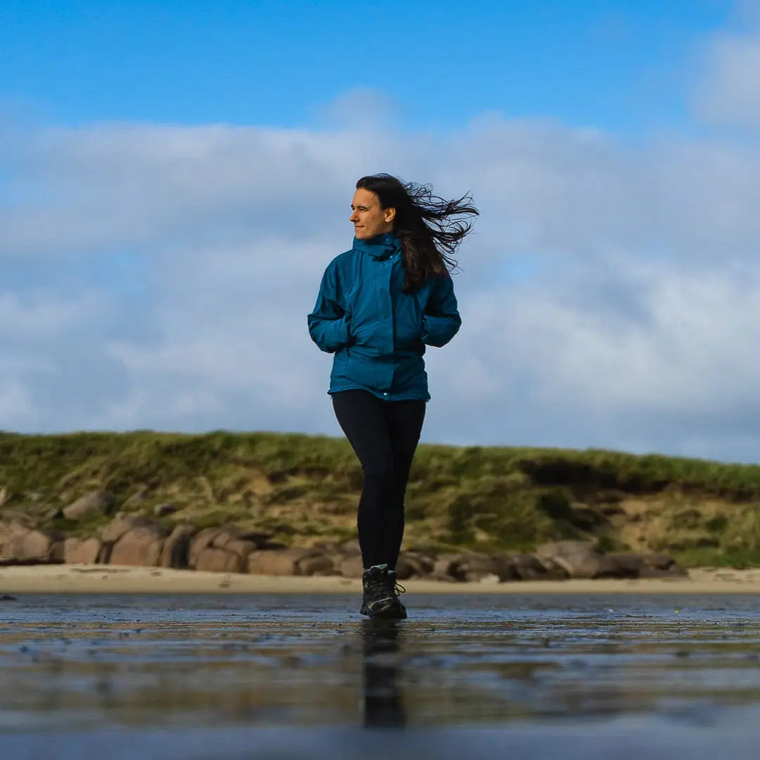 Woman in a blue Keela Womens Prosport Jacket strolling on a wet beach