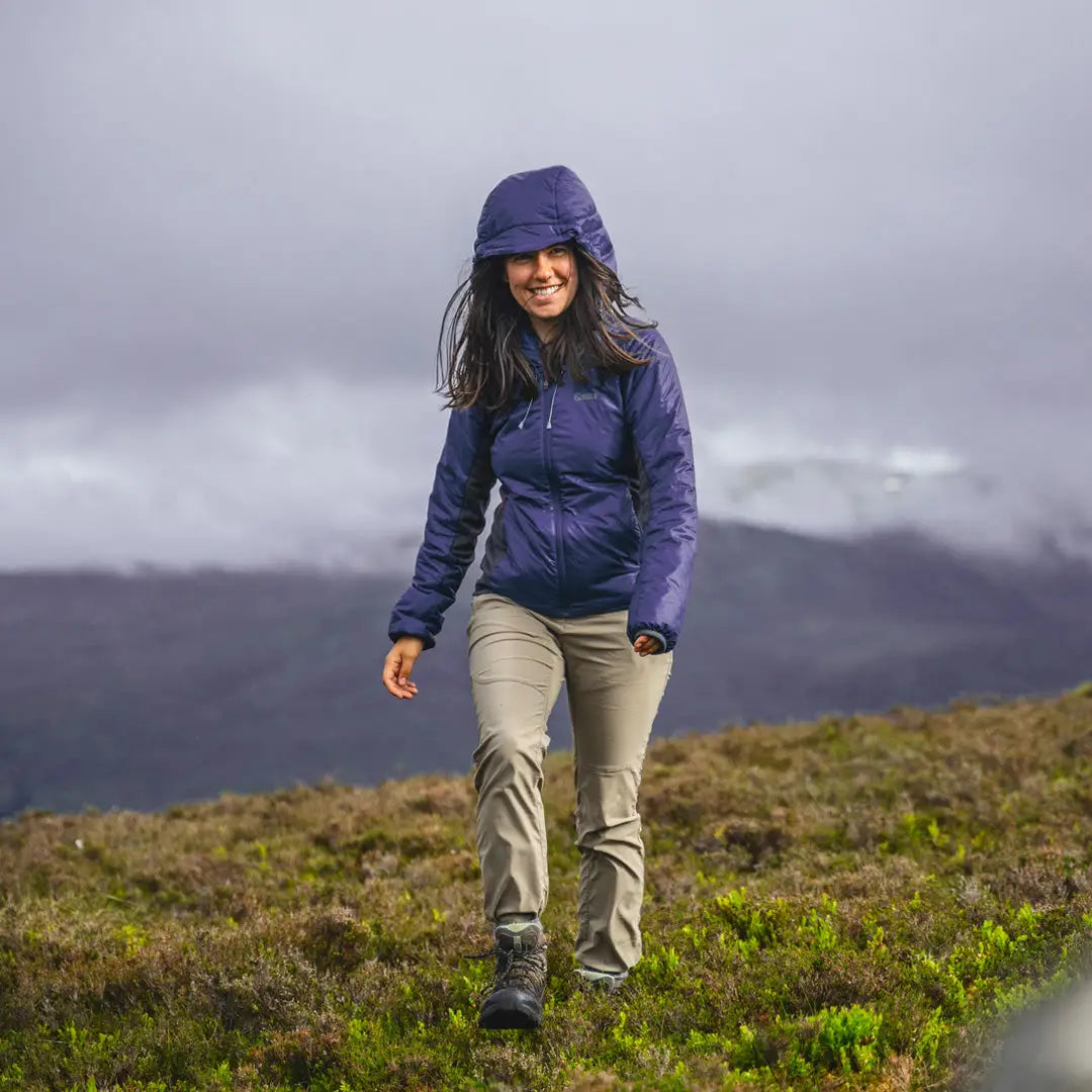 Woman hiking in Keela Womens Talus Primaloft Jacket on a sunny grassy hillside