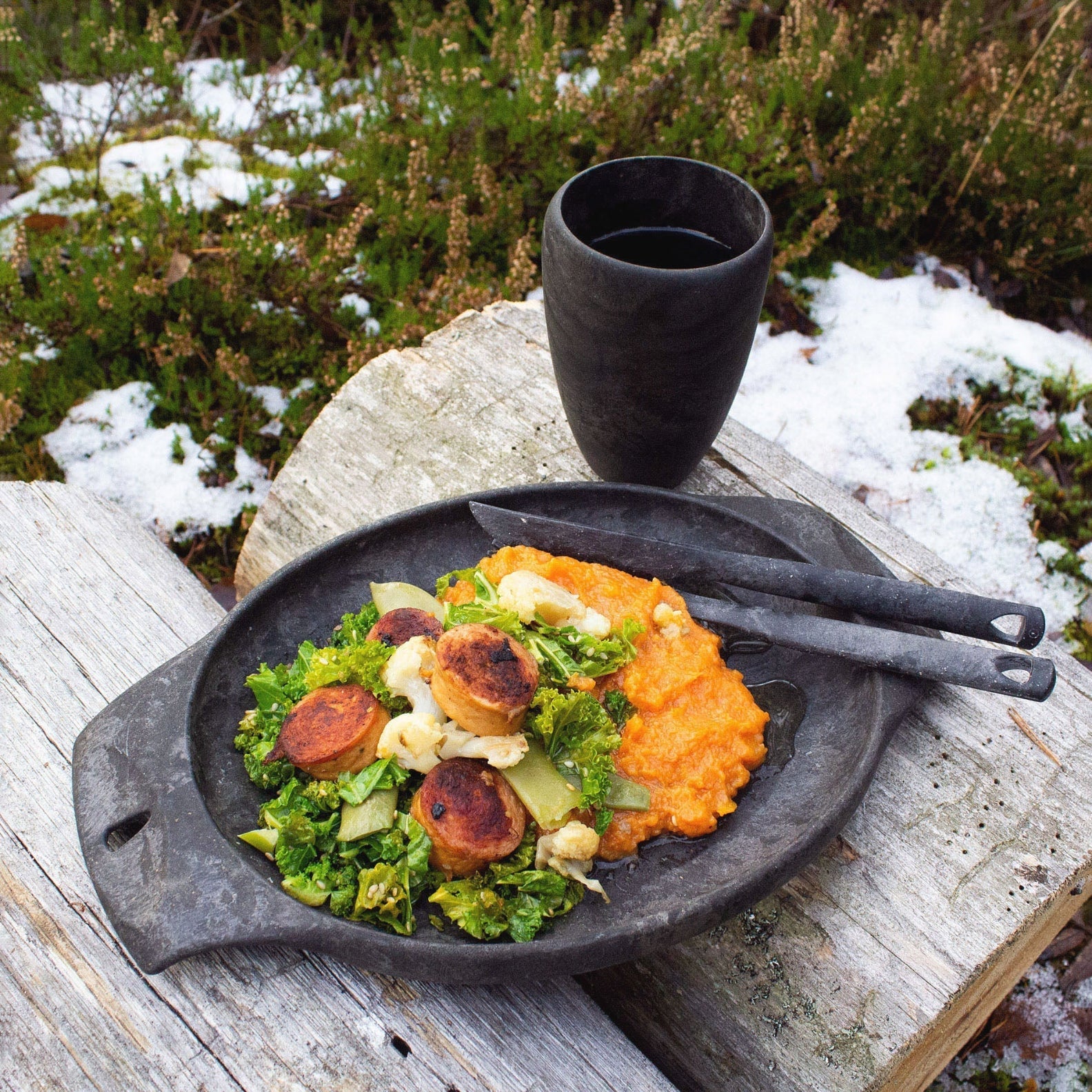 Rustic meal with sausage and greens in a Kupilka Cup, perfect for country clothing lovers