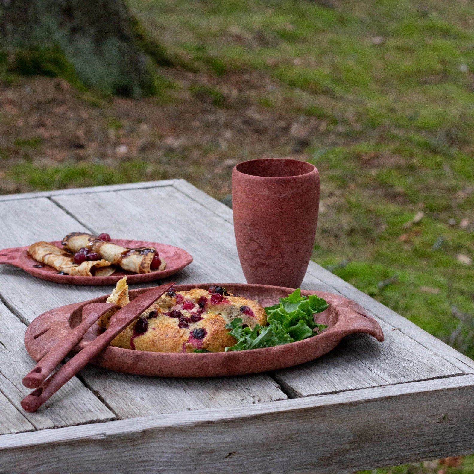 Rustic terracotta tableware with food and a Kupilka Cup for cozy country vibes