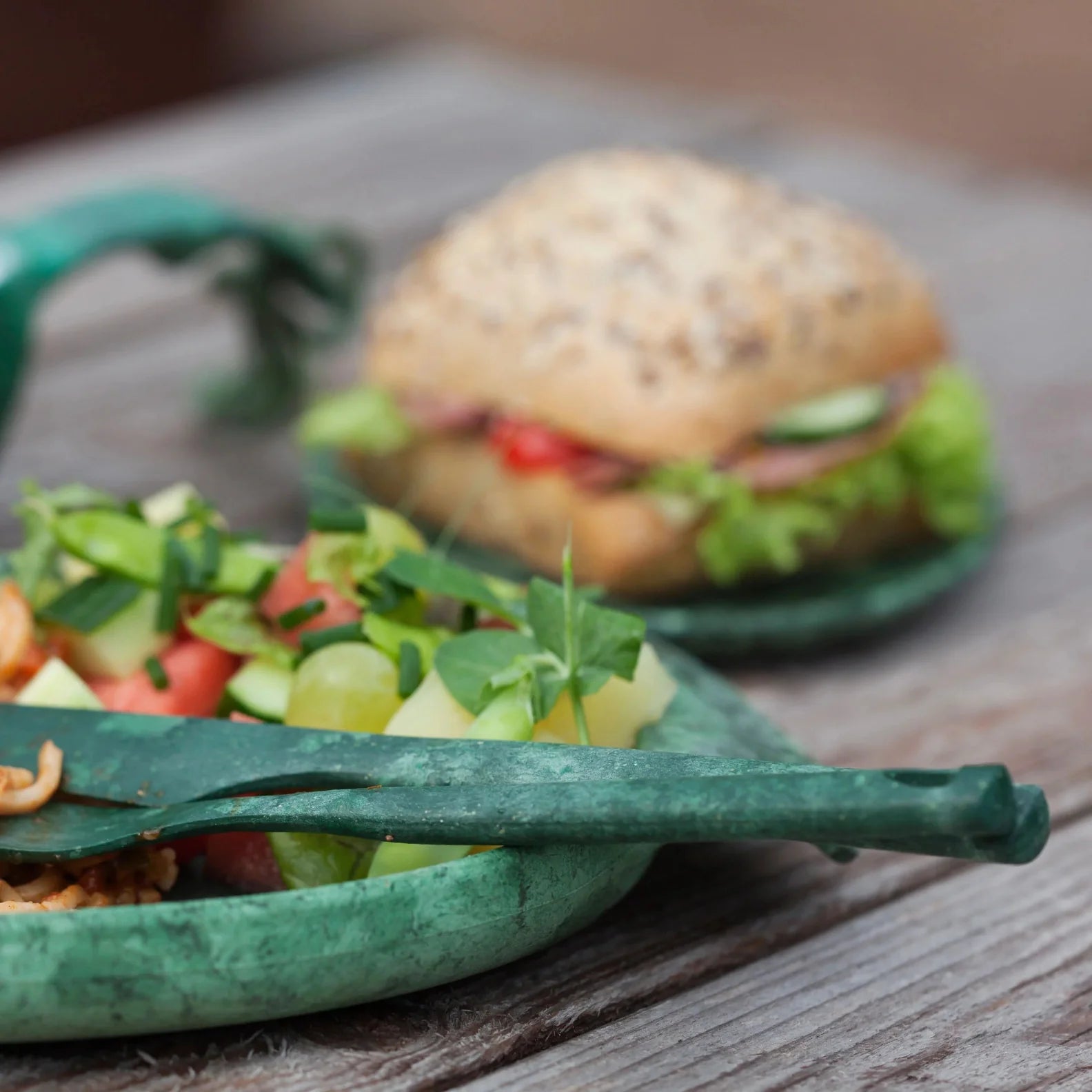 Salad and sandwich on green plates with Kupilka Cutlery Set for outdoor dining fun