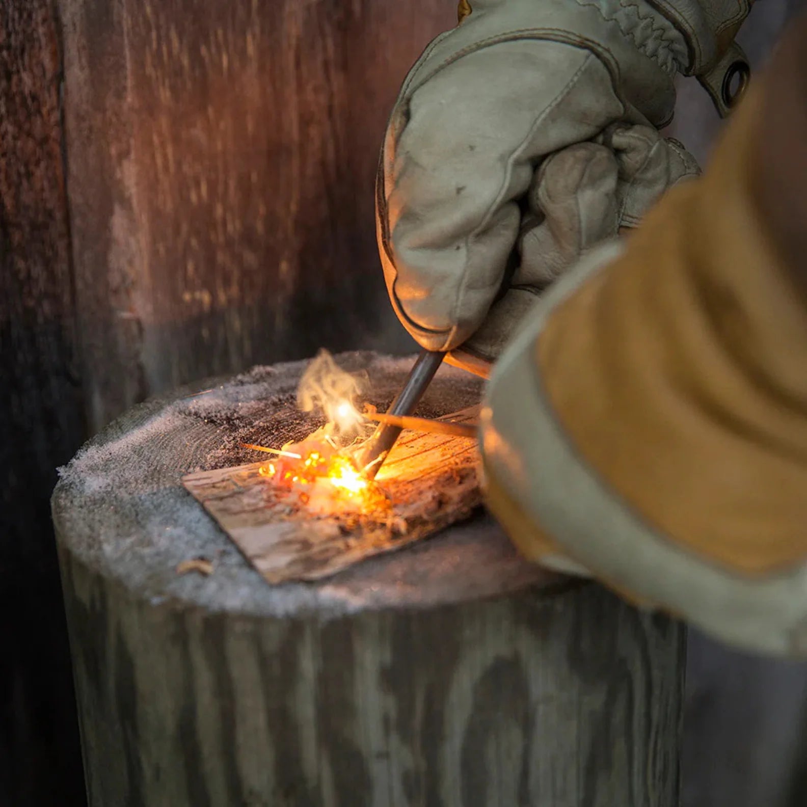 Gloved hands using Kupilka Firesteel to ignite tinder with a compact striker