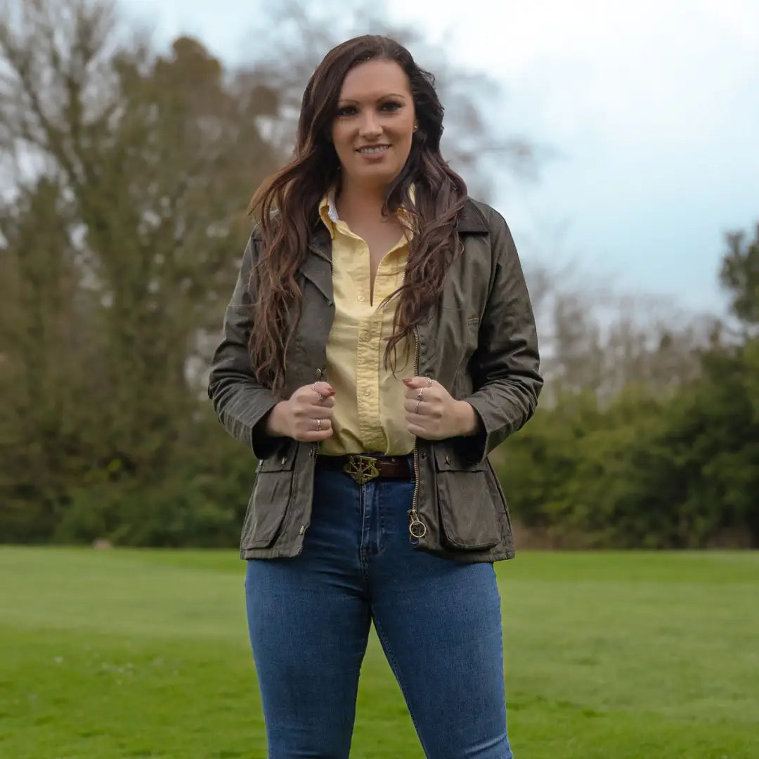 Woman in a green jacket and yellow shirt showcasing the Ladies Antique Wax Jacket outdoors