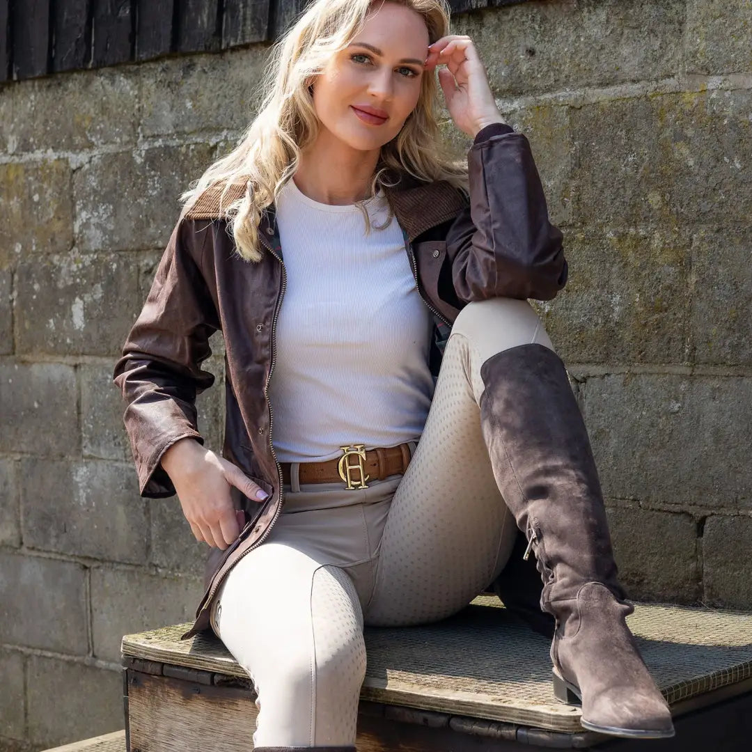 Woman in a brown leather jacket and beige pants styled with an antique wax jacket vibe