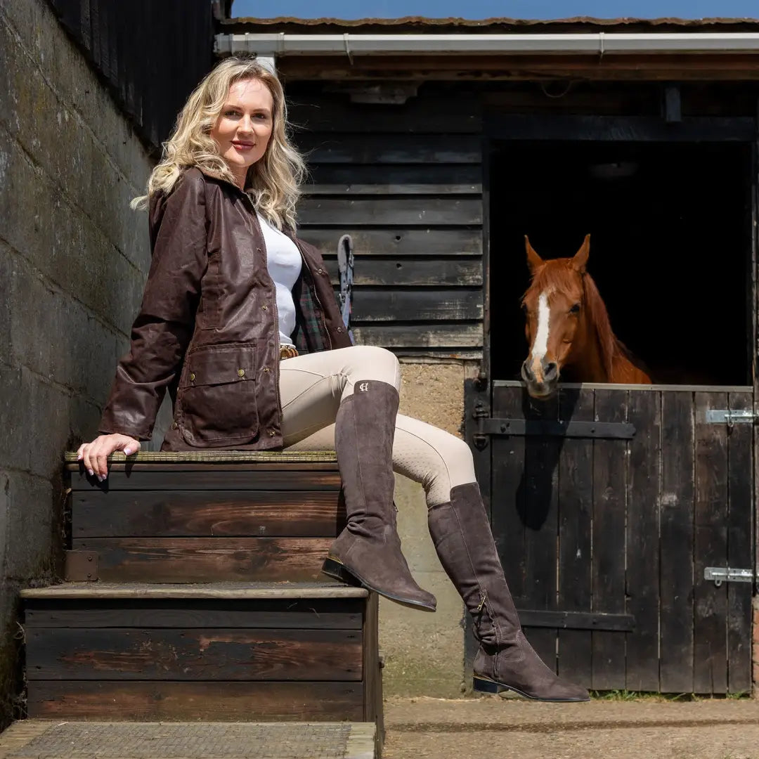 Woman in an Antique Wax Jacket sitting by a horse stable on wooden steps