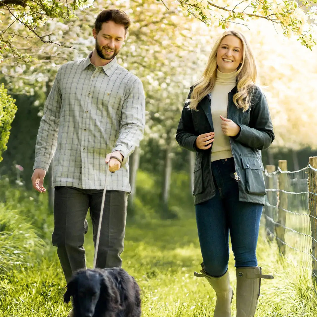 Couple walking a dog in a spring garden wearing an antique wax jacket