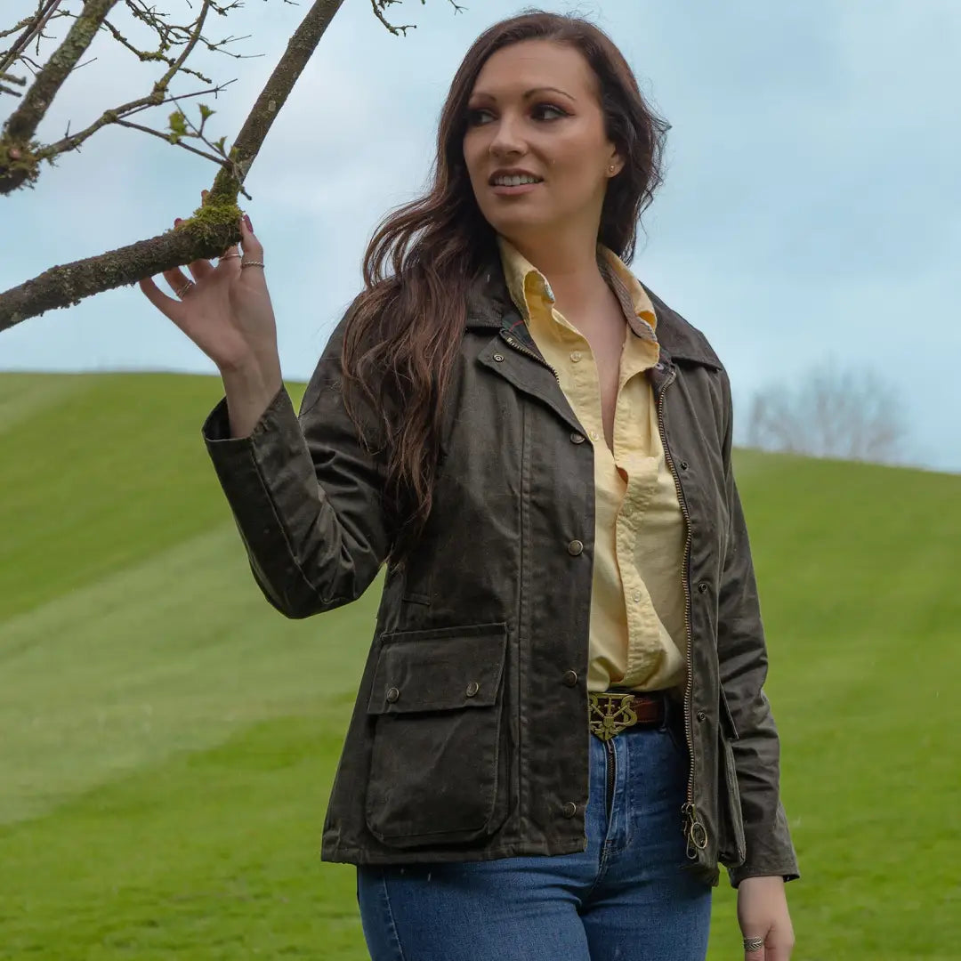 Woman in dark Antique Wax Jacket and yellow shirt by a tree branch outdoors