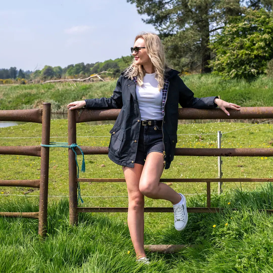 Woman in a Ladies Traditional Wax Jacket leaning on a wooden fence in the countryside