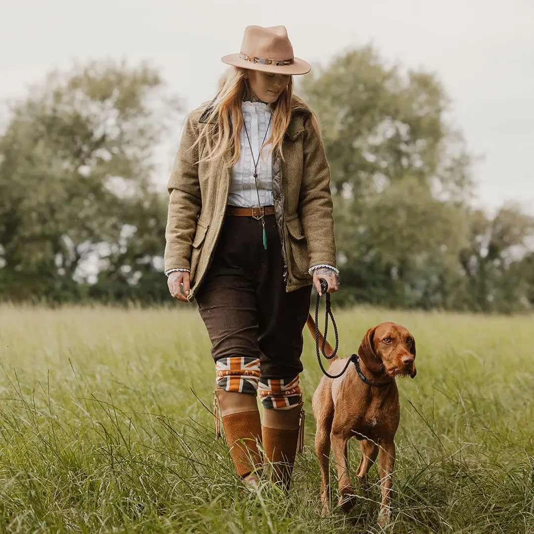 Woman in ladies tweed jacket walking a brown dog in a grassy field, fantastic quality