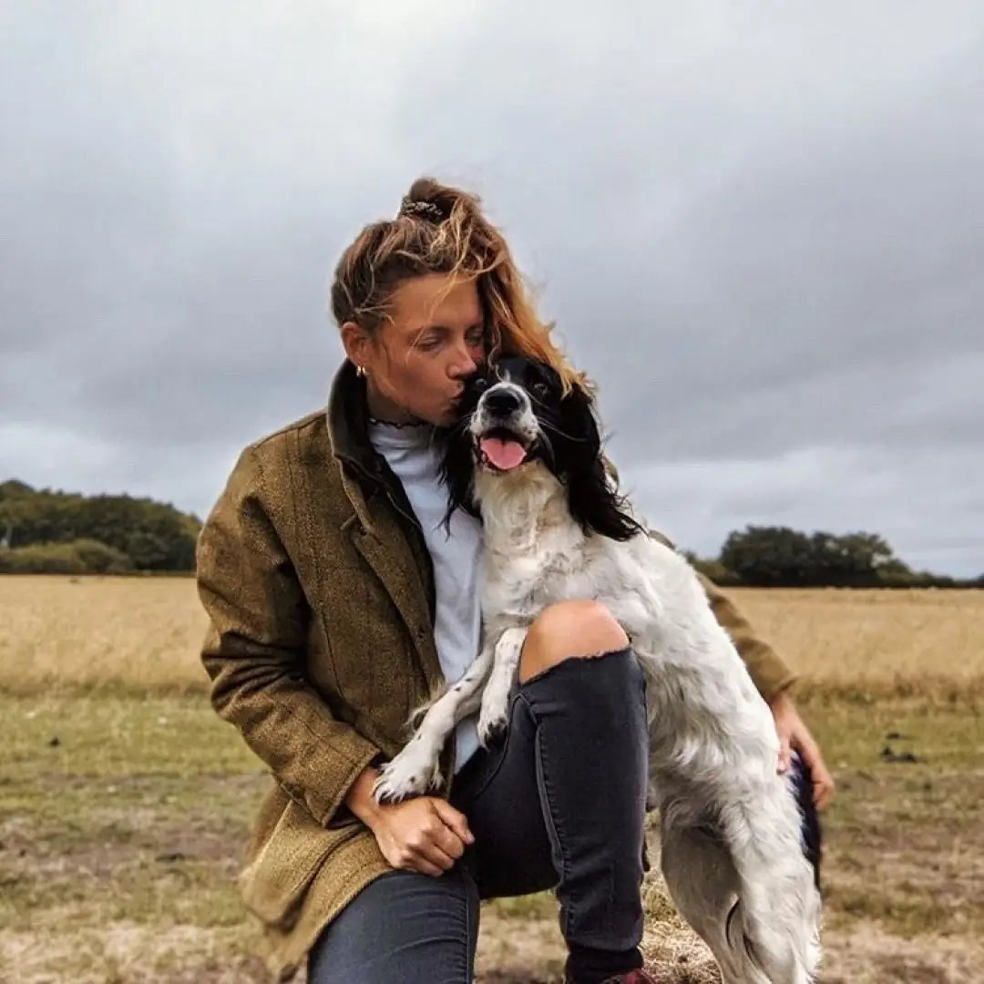 Person in a Ladies Tweed Jacket embracing a black and white spaniel outdoors