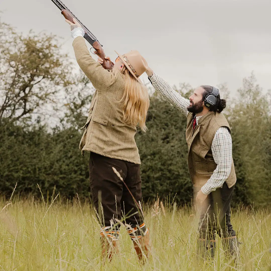 Person aiming a shotgun while wearing a stylish ladies tweed jacket in fantastic quality