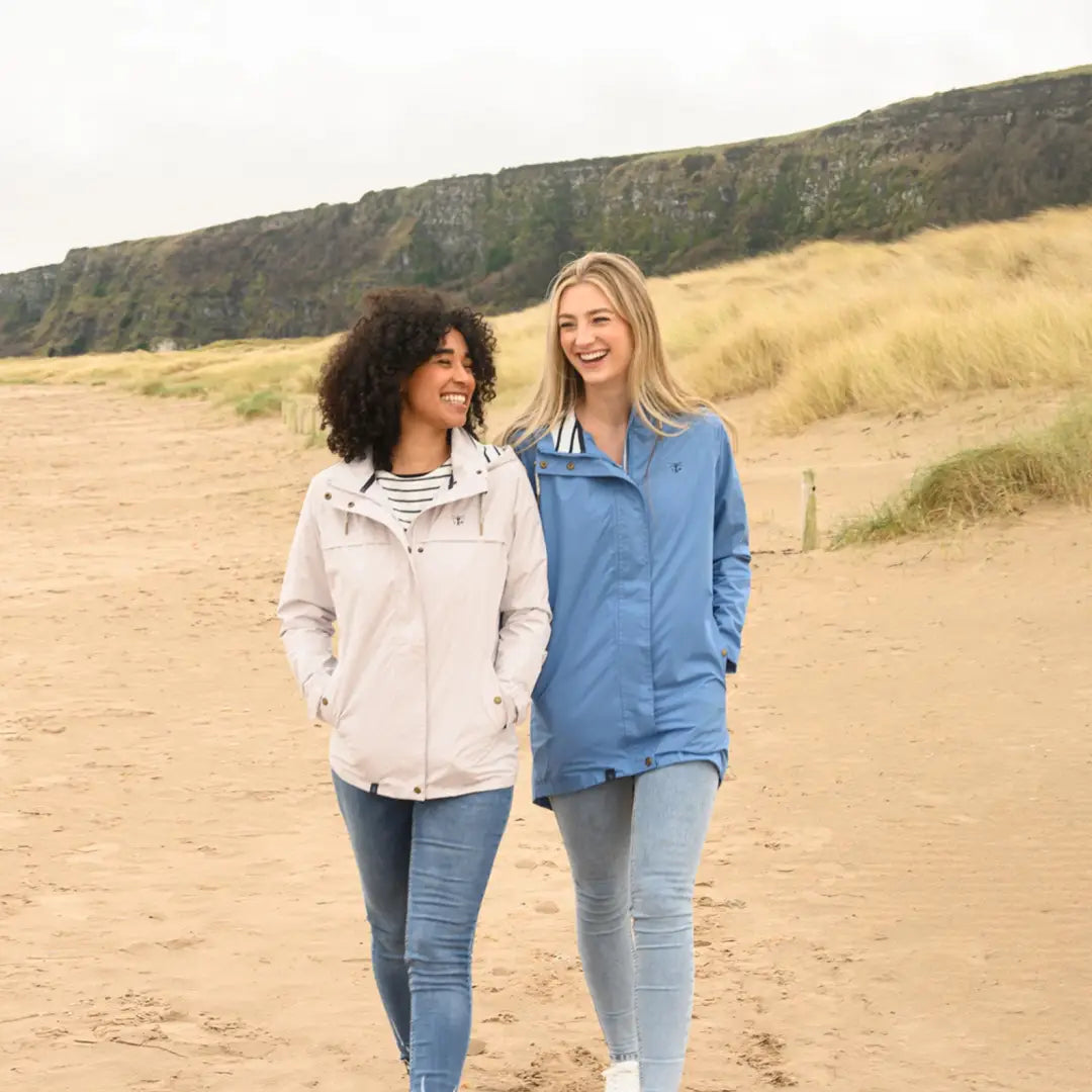 Two smiling women in Lighthouse Beachcomber Ladies Waterproof Jackets walking on the beach