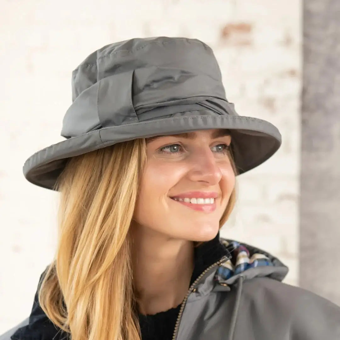 Smiling person in a gray Lighthouse Canterbury Waterproof Ladies Hat with blonde hair