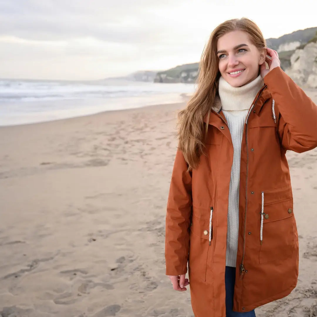 Woman in an orange Lighthouse Isobel Coat, featuring longer length faux fur, at the beach