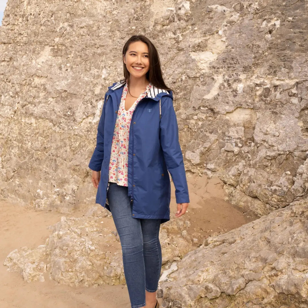 Woman in a blue Lighthouse Ladies Beachcomber Jacket against a stone wall