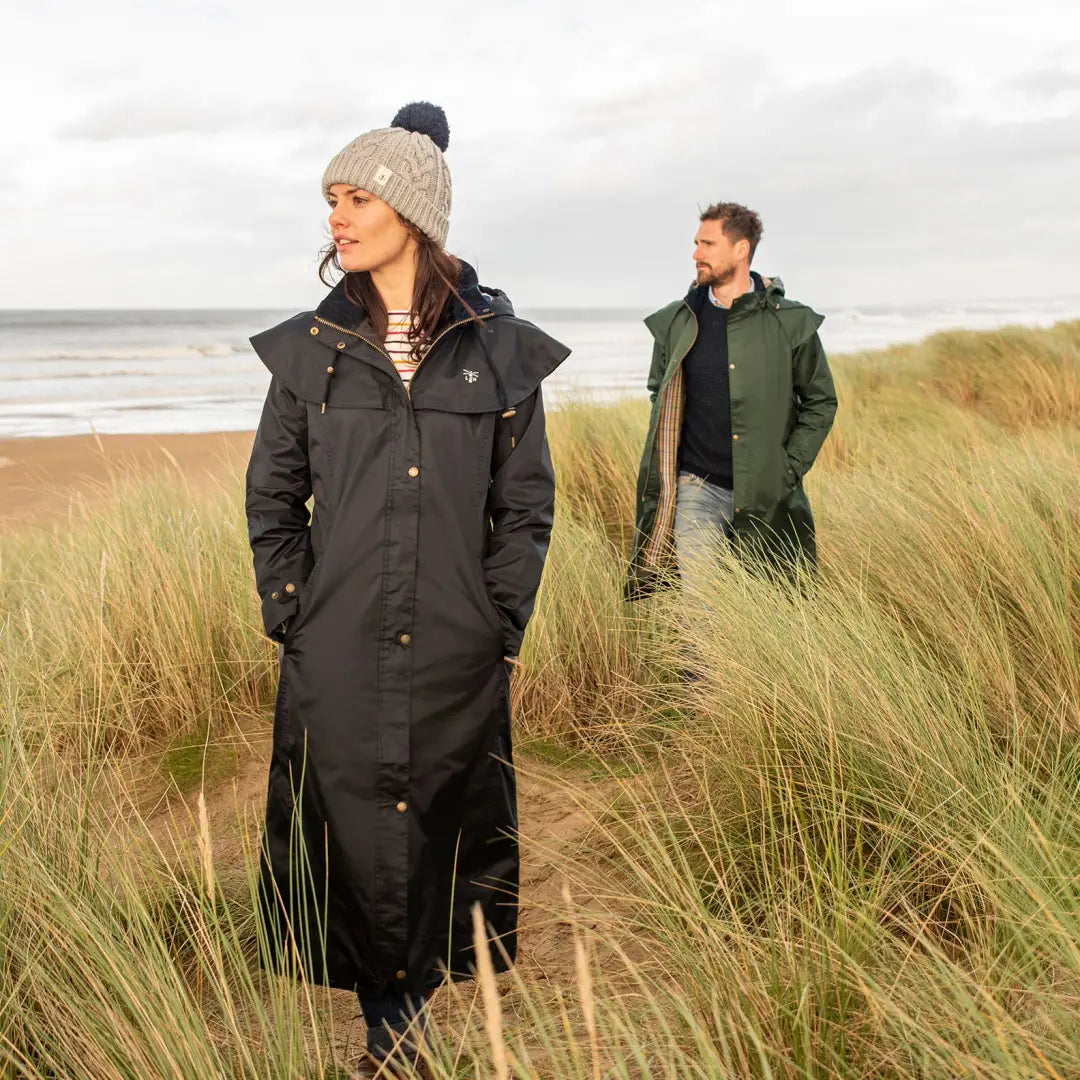 Two people in winter coats near beach grass, featuring Lighthouse Outback ladies waterproof raincoat