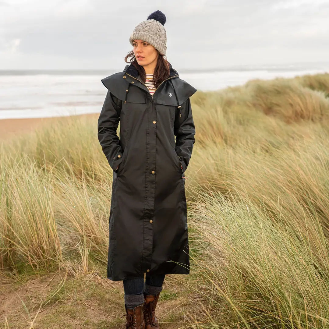 Long black Lighthouse Outback full length ladies waterproof raincoat on a beach