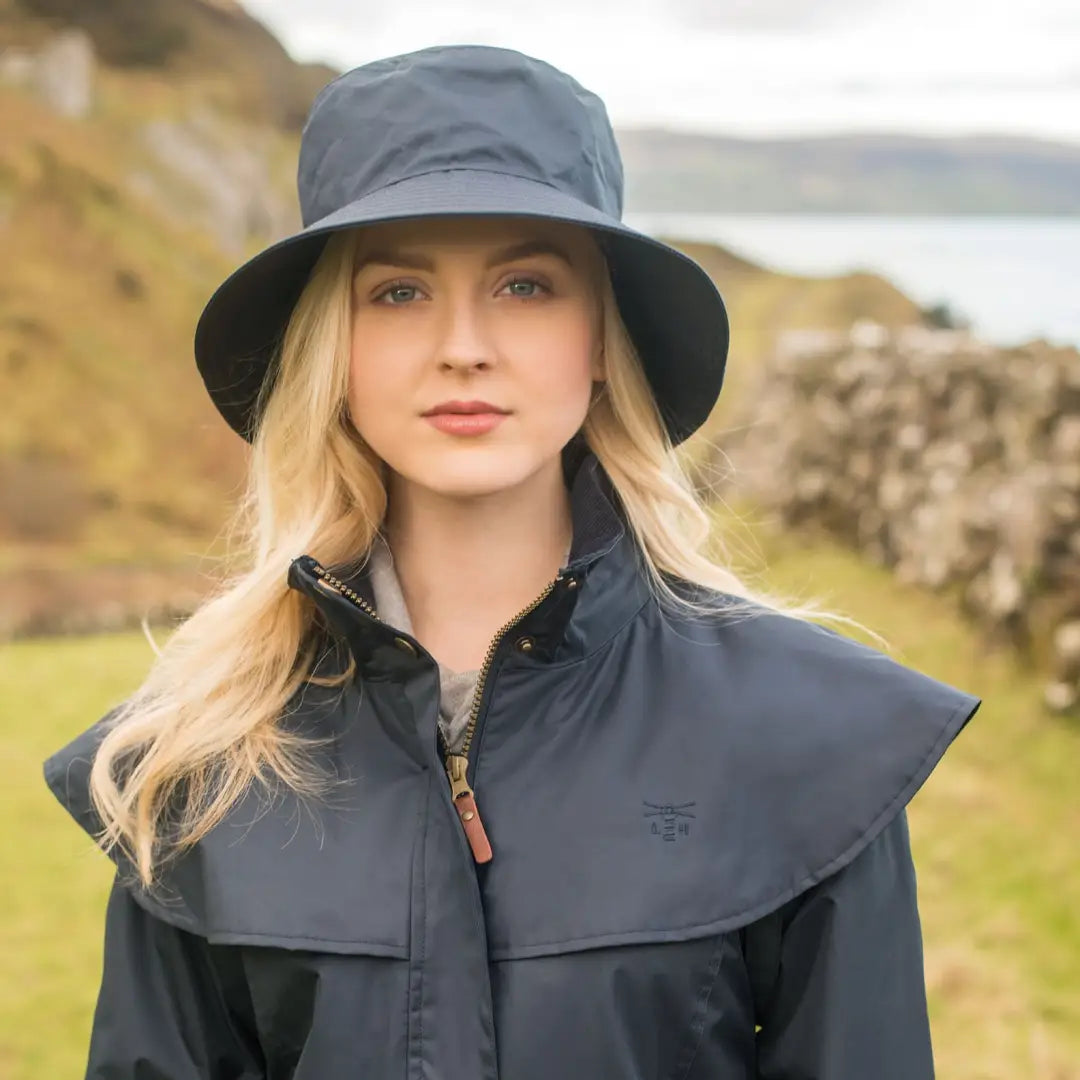 Woman in a navy blue rain hat and jacket showcasing a highly waterproof ladies waterproof raincoat