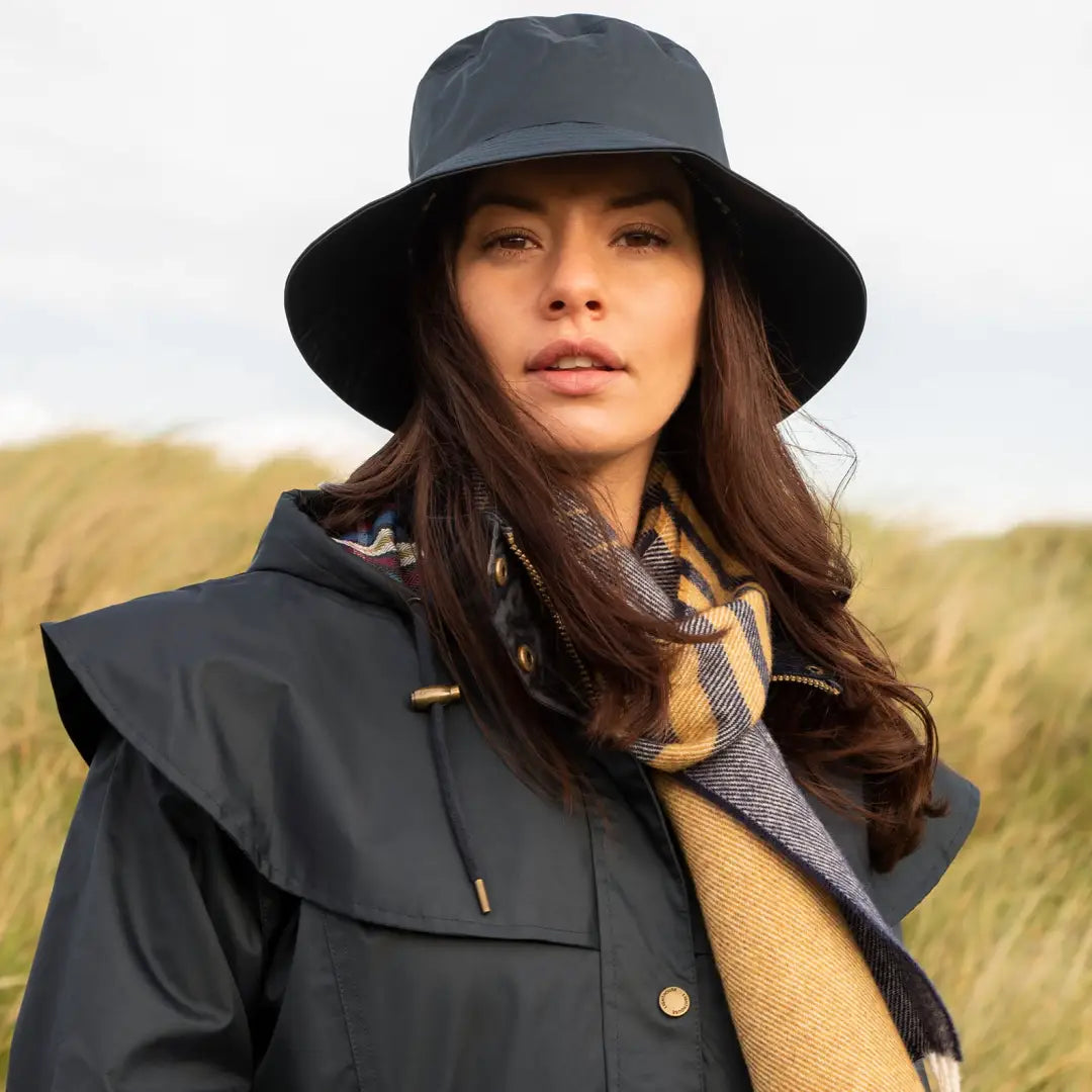 Woman in dark wide-brimmed hat and navy coat showcasing a highly waterproof ladies raincoat