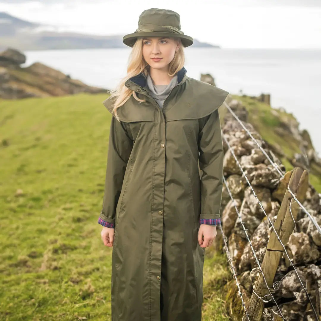 Woman in an olive green Lighthouse Outback full length ladies waterproof raincoat outdoors