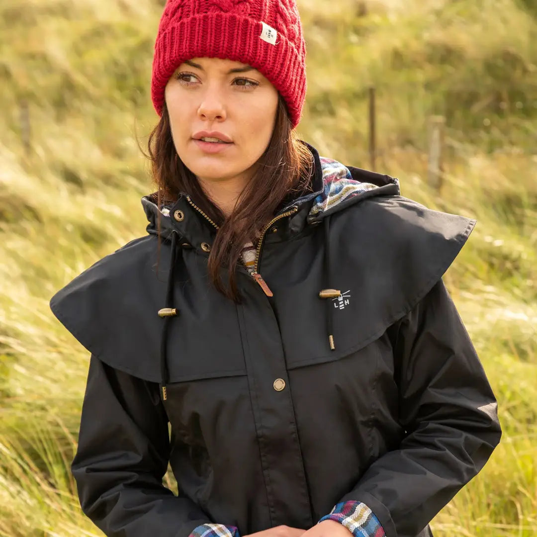 Woman in a black jacket and red knit hat wearing the Lighthouse Outback ladies waterproof raincoat