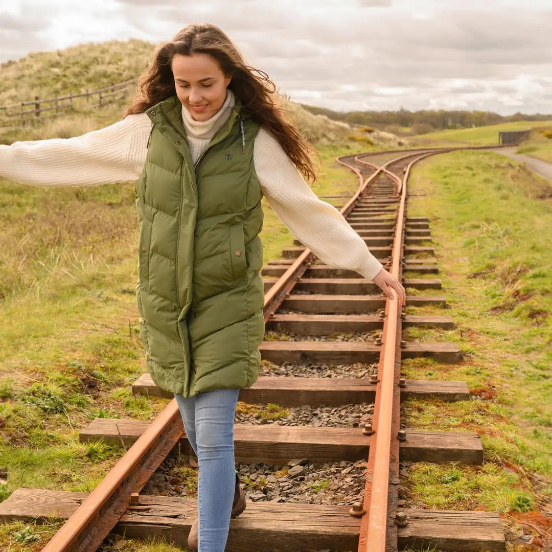 Woman in green puffy vest strolling railroad tracks, perfect for a winter city break