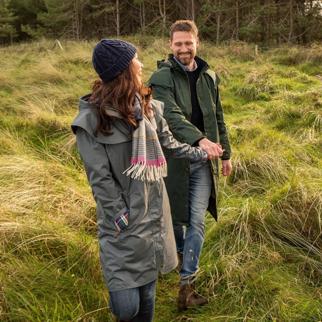 Couple wearing Lighthouse Stockman Full Length Waterproof Rain Coat walking in a field