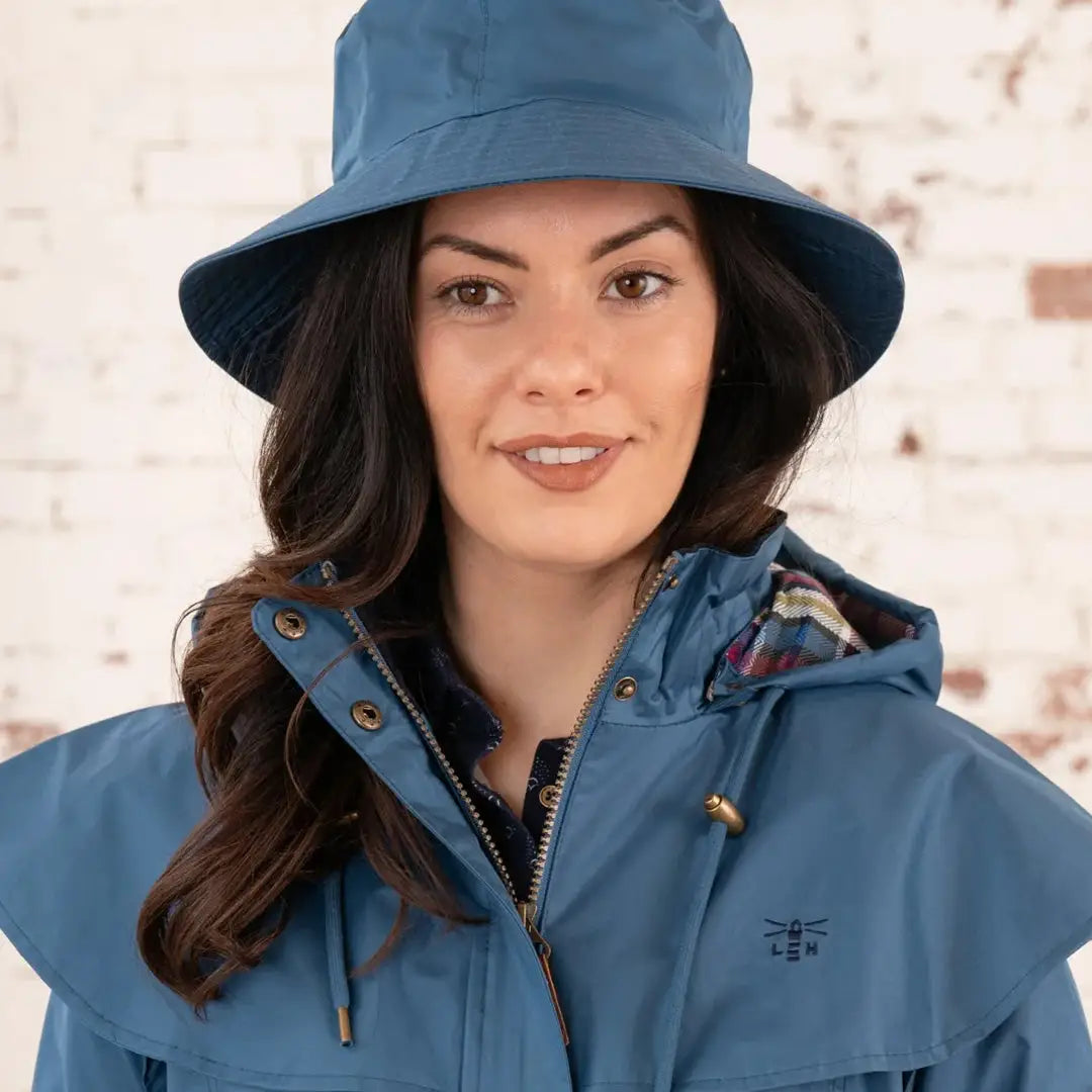 Woman in a blue bucket hat and jacket from the Lighthouse Storm Waterproof collection