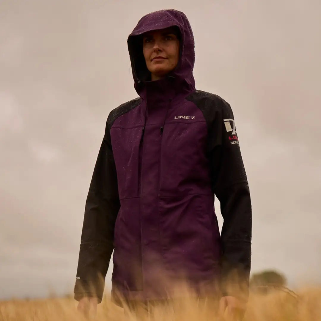 Person in a purple and black hooded Storm Pro20 jacket outdoors showcasing peak level style