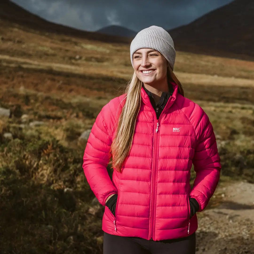 Smiling woman in a bright pink puffer jacket showcasing the Sac Ladies Synergy Jacket