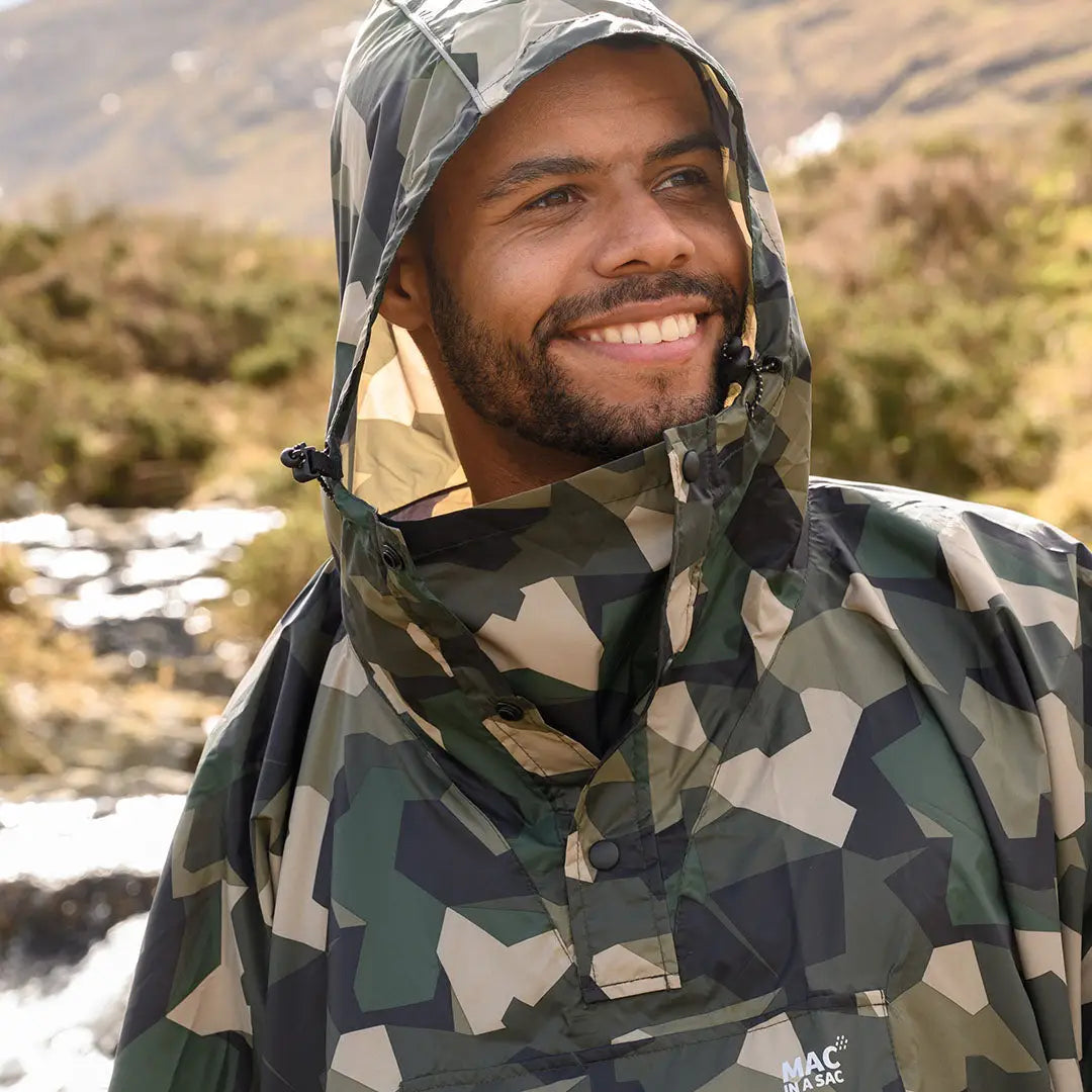 Smiling person rocking a Camouflage Mac In A Sac Origin 2 Poncho with a hood