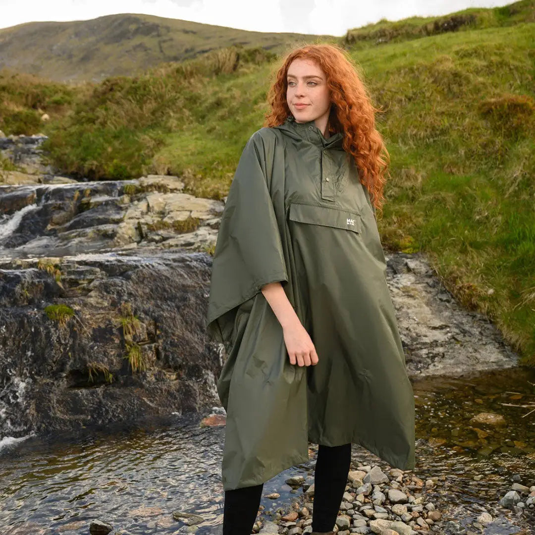 Person with curly red hair wearing a Green Mac In A Sac Origin 2 Poncho outdoors