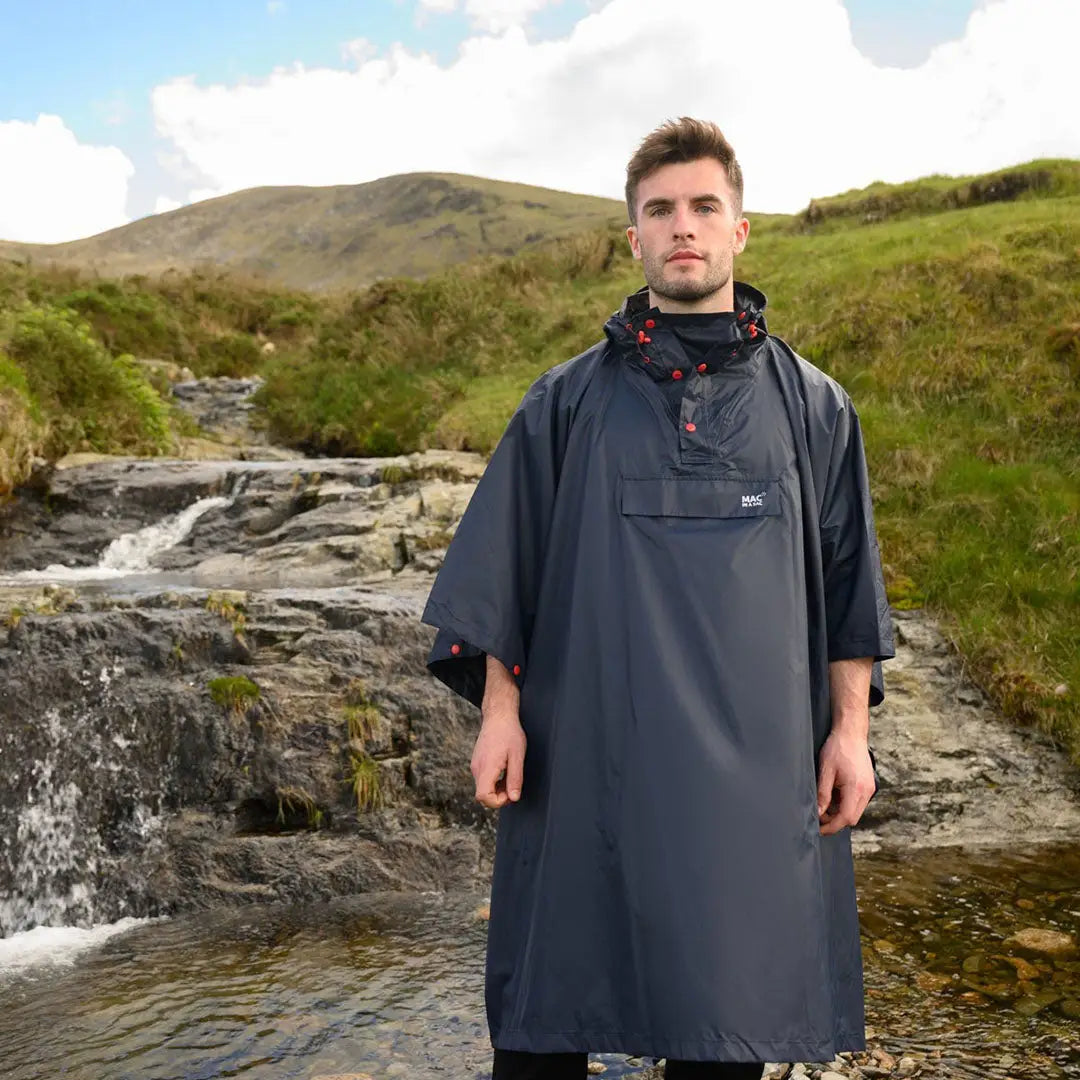 Person wearing Mac In A Sac Origin 2 Poncho near a waterfall, embracing country clothing style