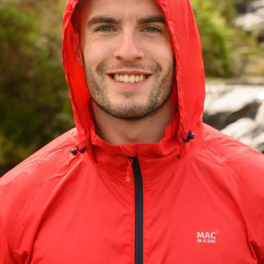 Smiling person in a bright red Mac in a Sac Origin waterproof jacket for adults