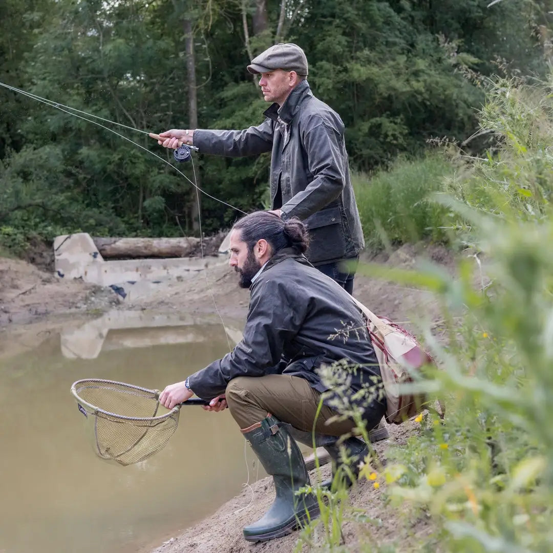 Two men wearing Mens Classic Antique Wax Jackets fishing at a muddy pond