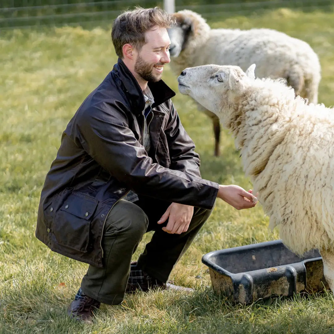 Sheep and person in a field wearing a Mens Classic Antique Wax Jacket