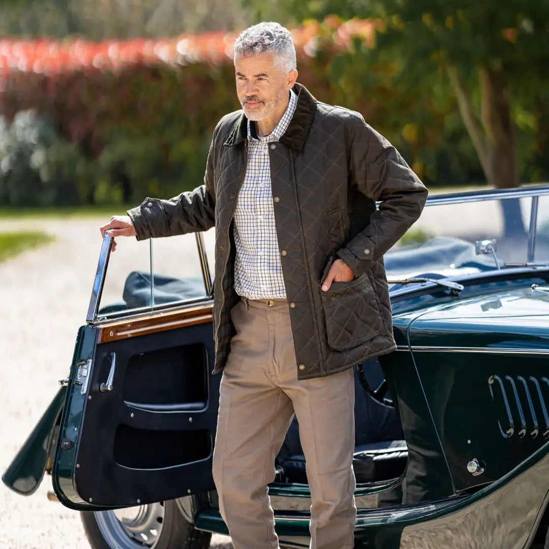 Middle-aged man in a vintage convertible wearing a stylish quilted wax jacket