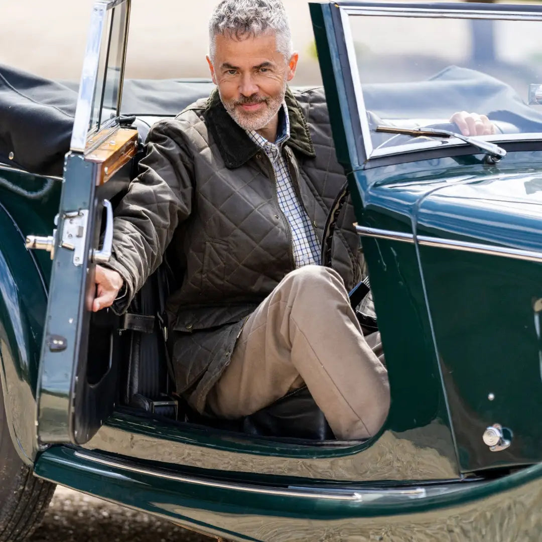 Man in a Mens Quilted Wax Jacket exiting a vintage green sports car