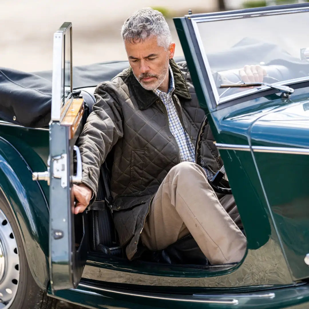 Middle-aged man with gray hair in a Mens Quilted Wax Jacket by a vintage green convertible